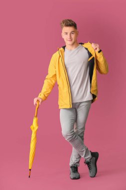 Renkli arka planda şemsiyesi olan genç adam