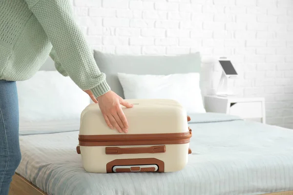 若い女性のベッドの上にスーツケースを置くホテルの部屋 — ストック写真
