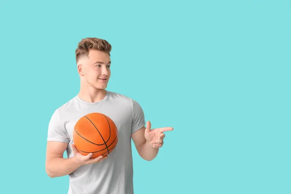 Junger Mann Mit Ball Zeigt Etwas Auf Farbigem Hintergrund — Stockfoto