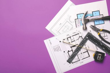 İnşaatçının malzemeleriyle şerit ölçümü ve renk arkaplanı üzerine planlar