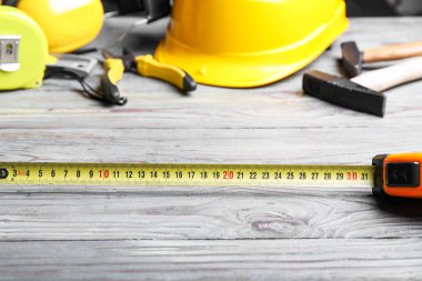 Ahşap arka planda inşaat malzemeleriyle şerit ölçümü