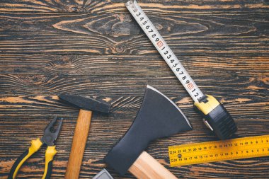Ahşap arka planda inşaat malzemeleriyle şerit ölçümü