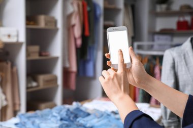 Modern kıyafet mağazasında cep telefonu olan bir kadın.