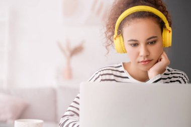 Evde online öğrenim için dizüstü bilgisayar kullanan genç bir kadın