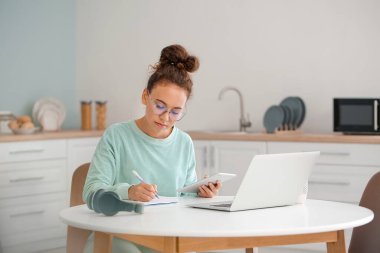 Evde online öğrenim için tablet bilgisayar ve dizüstü bilgisayar kullanan genç bir kadın