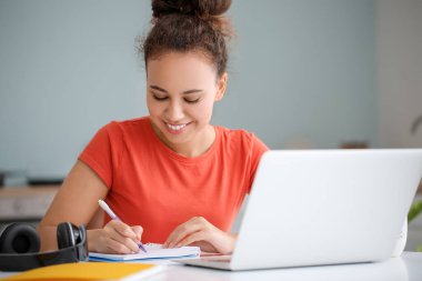 Evde online öğrenim için dizüstü bilgisayar kullanan genç bir kadın