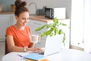 Evde online öğrenim için dizüstü bilgisayar kullanan genç bir kadın