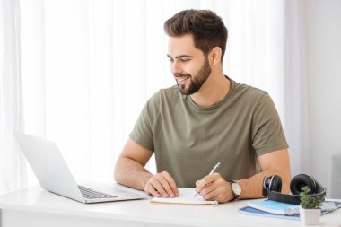 Genç adam evde online öğrenim için dizüstü bilgisayar kullanıyor