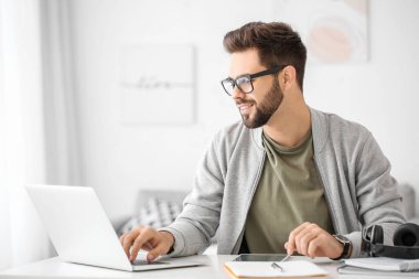 Genç adam evde online öğrenim için dizüstü bilgisayar kullanıyor