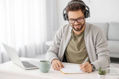 Genç adam evde online öğrenim için dizüstü bilgisayar kullanıyor