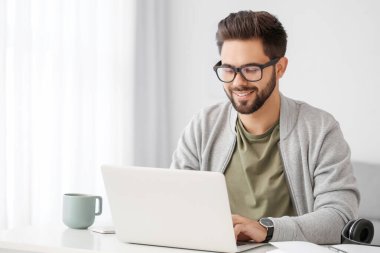 Genç adam evde online öğrenim için dizüstü bilgisayar kullanıyor