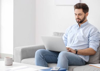 Genç adam evde online öğrenim için dizüstü bilgisayar kullanıyor