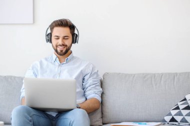 Genç adam evde online öğrenim için dizüstü bilgisayar kullanıyor