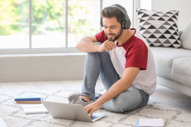 Genç adam evde online öğrenim için dizüstü bilgisayar kullanıyor