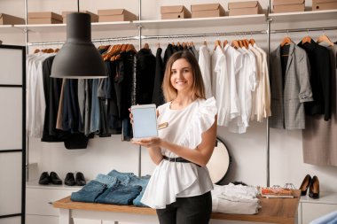 Modern giyim mağazasında tablet bilgisayarlı kadın satıcı