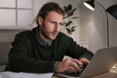 Genç adam evde online öğrenim için dizüstü bilgisayar kullanıyor