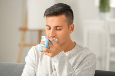 Evde çay içen yakışıklı genç adam.
