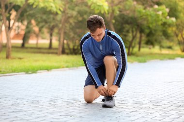 Spor ayakkabı bağcıklarını bağlayan genç bir adam.
