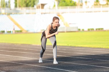 Stadyumda koşan genç bir bayan.