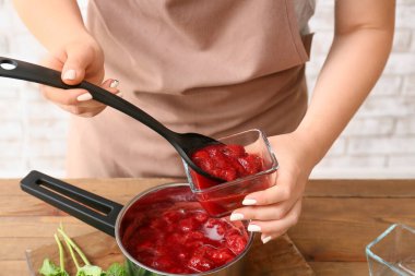 Kadın mutfakta tatlı çilek reçeli yapıyor, yakın plan.