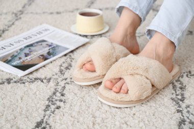 Evde yumuşak terlikli genç bir kadın var.