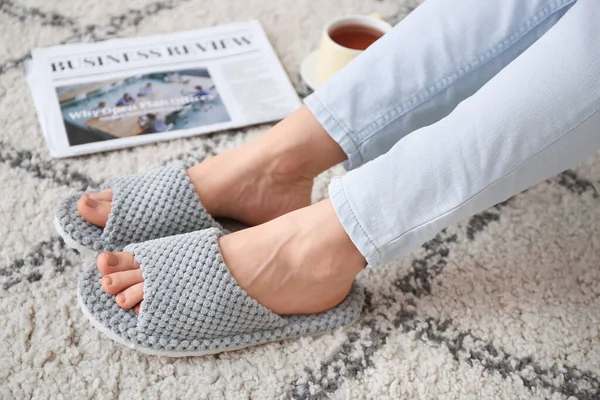 Evde yumuşak terlikli genç bir kadın var.