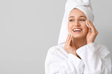 Gri arka planda pamuk pedleri olan güzel genç bir kadın.