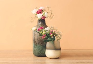 Masanın üzerinde renk zeminine karşı çiçekli güzel vazolar