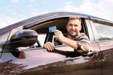 Ehliyet sınavını başarıyla geçtikten sonra mutlu genç adam.