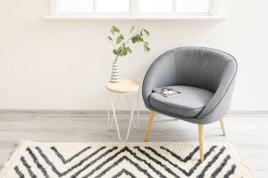 Koltuğu, masası ve güzel halısı olan modern bir oda.