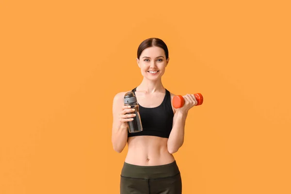 Sportliche Junge Frau Mit Wasserflasche Und Hantel Auf Farbigem Hintergrund — Stockfoto