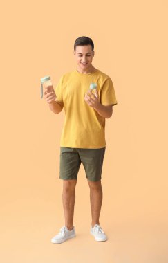 Renkli arka planda su şişeleri olan sportif bir genç adam.