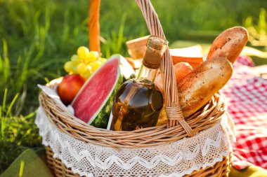 Parkta romantik piknik için içinde lezzetli yemekler ve içecekler olan sepet.