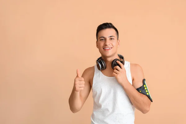 Sportowy Młody Człowiek Słuchawkami Pokazującymi Kciuk Góry Kolorowym Tle — Zdjęcie stockowe