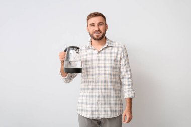 Arka planda elektrikli su ısıtıcısı olan genç bir adam.