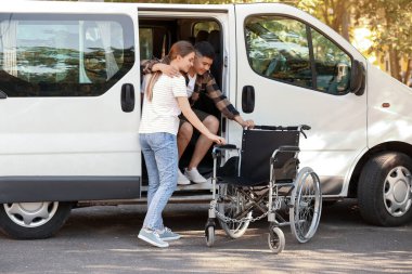 Engelli kocasına minibüsten inmesi için yardım eden kadın.