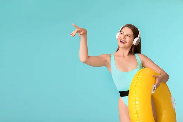 Young Woman Headphones Inflatable Ring Showing Something Color Background — Stock Photo, Image