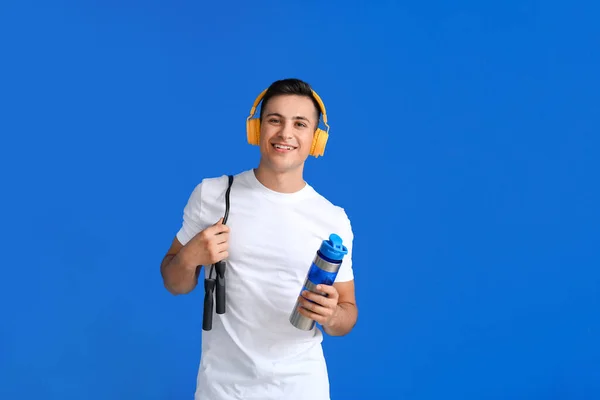 Sportlicher Junger Mann Mit Kopfhörern Und Wasser Auf Farbigem Hintergrund — Stockfoto