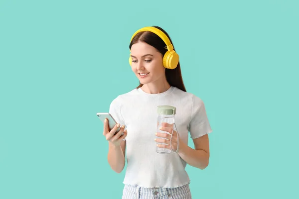 Jeune Femme Avec Bouteille Eau Écoutant Musique Sur Fond Couleur — Photo