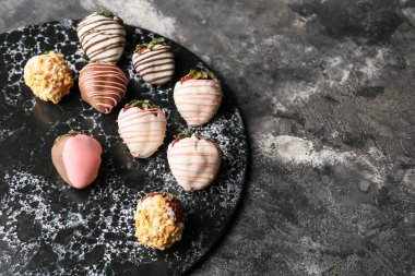 Koyu arkaplanda çikolataya batırılmış lezzetli çilek.