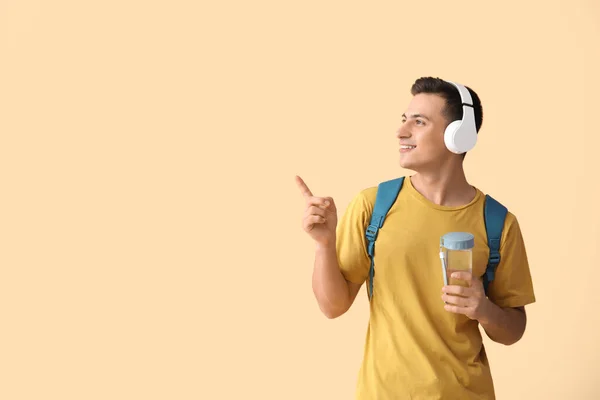 Young Man Bottle Water Headphones Pointing Something Color Background — Stock Photo, Image