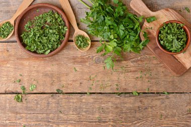 Ahşap arka planda taze ve kuru maydanoz.