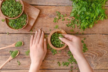 Ahşap arka planda kuru ve taze maydanozlu kadın elleri