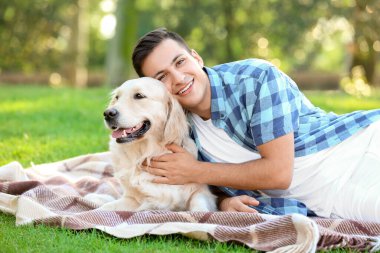 Parkta güzel köpeği olan genç bir adam dinleniyor.
