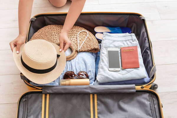 Woman packing suitcase at home. Travel concept