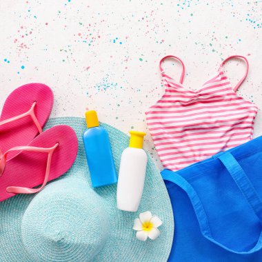 Beyaz arka planda güneş kremi ve aksesuarlı plaj çantası.