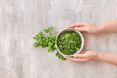 Gri arka planda kuru maydanozlu kadın elleri