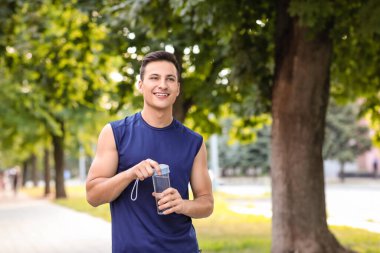 Parkta bir şişe suyu olan genç bir sporcu.