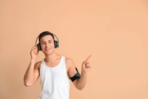 Joven Deportivo Con Auriculares Apuntando Algo Fondo Color — Foto de Stock