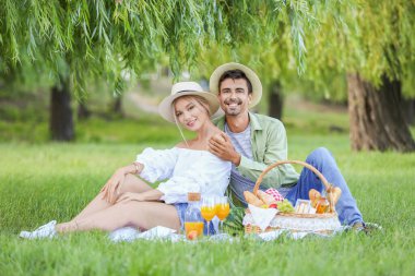 Mutlu genç çift parkta piknik yapıyor.